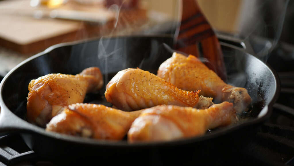 Pilons de poulet rôtis au paprika fumé et curcuma, servis dans une poêle ou sur assiette, peau croustillante et dorée, accompagnements variés, scène de cuisine maison chaleureuse, style culinaire éditorial.