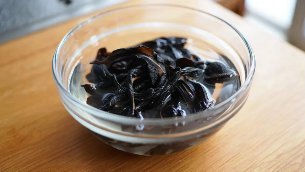 Recette Ramen aux Champignons et Crevettes : Soupe Japonaise Authentique en 16 Minutes 2 Un bol fumant de recette ramen japonais traditionnel, avec des nouilles parfaitement cuites baignant dans un bouillon parfumé et riche. Garni de crevettes tendres, de champignons noirs, de lamelles de carottes croquantes, de pousses d’épinards frais et de coriandre ciselée. Servi dans un bol en céramique avec des baguettes et une cuillère chinoise, ce plat réconfortant est décoré d’un quartier de citron vert pour une touche d’acidité.